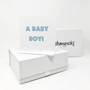 new baby by gift with card in blue font and shmuncki gift boxes